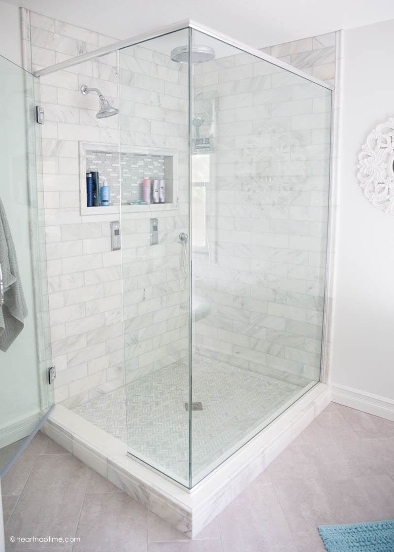 Bathroom makeover via I Heart Naptime: Grey and white bathroom remodel with Carrara marble herringbone tile tile, white vintage tub and blue accents. 