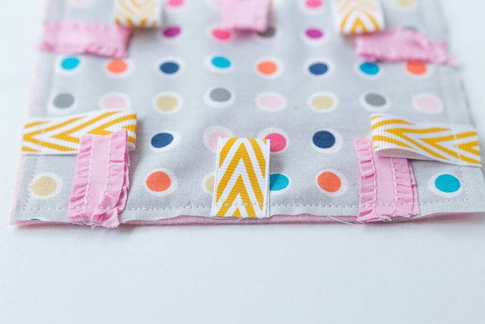 Taggie Baby Toy - a simple sewing project perfect for any new baby. Colorful ribbons and a bright pattern makes this a great sensory toy for your little one. 