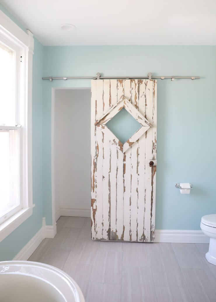 Fixer Upper Bathroom Before and Afters... fixer upper style bathroom makeover with clawfoot tub, watery paint color and sliding barn door.