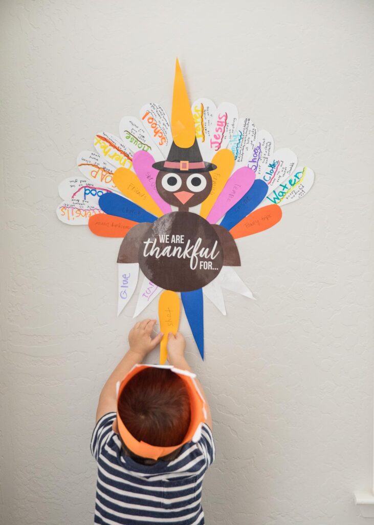 boy putting up paper turkey on wall