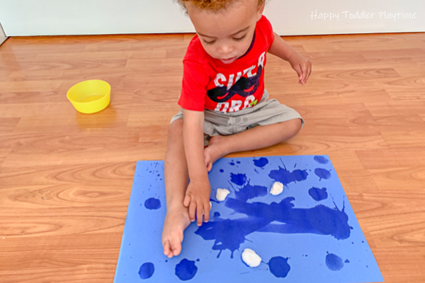 little boy painting with water and cotton balls