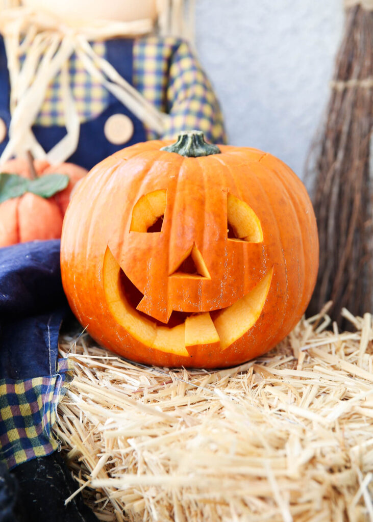 carved pumpkin on hay stack