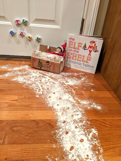 Elf sitting in a package with flour dust on floor.