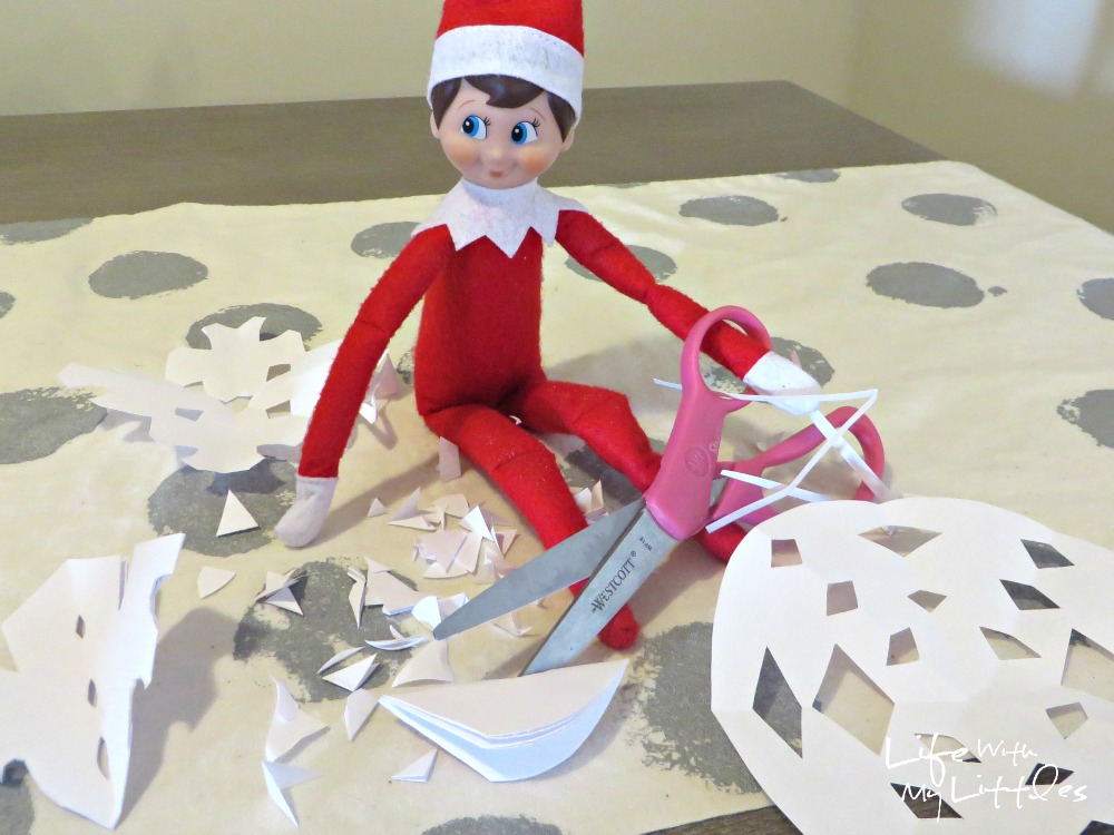 Elf cutting snowflakes out of paper. 